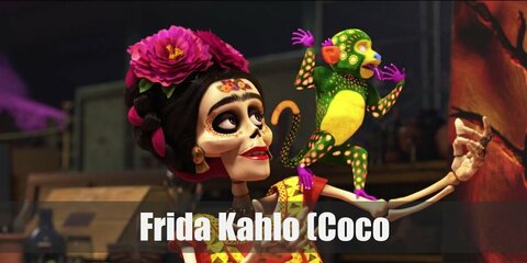 Frida Kahlo’s costume is an orange crop top, a ruffled magenta midi skirt, a flower crown, a brunette wig in an up-do, and face paint to look like a skeleton.