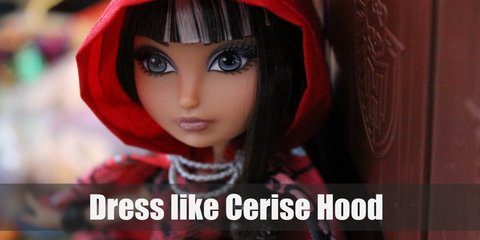 Cerise Hood wears a plaid red and black top with skater skirt, leggings, and a red hooded cape. She also has brown hair with white streaks, wears a pair of brown wedge boots, and carries a black picnic basket. 
