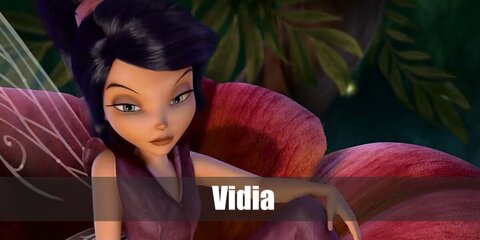  Vidia’s costume is a sleeveless dark purple V-neck shirt with a collar, dark purple boot-cut pants, slip-on purple shoes, a thirteen-panel wine red dance skirt, fairy wings, and has long black beehive hair styled with a dark red headband.