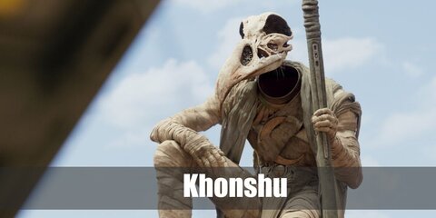  Khonshu’s costume is a white long sleeve shirt, white pants, white shoes all hidden underneath rolls of gauze, a tattered cape, bronze symbols on his neck and chest, his iconic bone mask, and his moon staff.