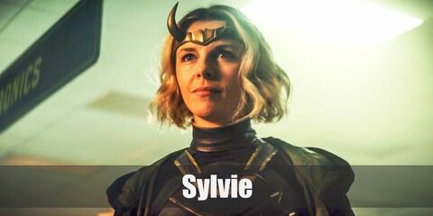  Sylvie’s costume is a black turtleneck top, harem pants, gold armor, black combat boots, a black and green hooded robe, and her signature gold horned crown.