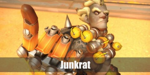  Junkrat’s costume is ripped camo pants, brown boots, a big ‘mine’ bag with canisters, a metal arm, and a metal leg.