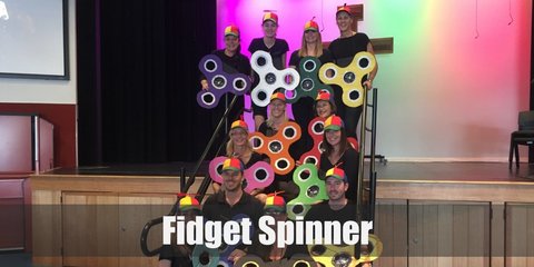 The fidget spinner costume can be done with carboard cutouts of petals joined at the edges to form the silhouette. Spray paint it to the desired color and add a layer of paint for the circular details on each prong.