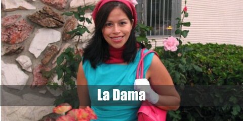 La Dama costume is a collared red button-up blouse, a two-piece set featuring a long-sleeved business blazer and a pencil cut skirt, closed-toe red pump shoes, a retro white silk neck scarf, a red air hostess pillbox hat, and wrist length white gloves for the La Dama Loteria Card.