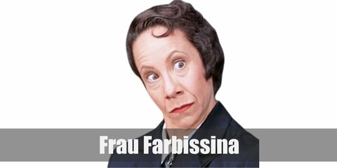 Frau Farbissina's costume is composed of a white button-down shirt with necktie and pants under a trench coat. She has a short brown bob and can be seen carryin a golf club.