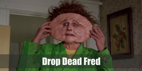  Drop Dead Fred’s costume is a yellow shirt and white suspenders underneath a green blazer, green-striped dress pants, red Oxfords, and his signature messy ginger hair.