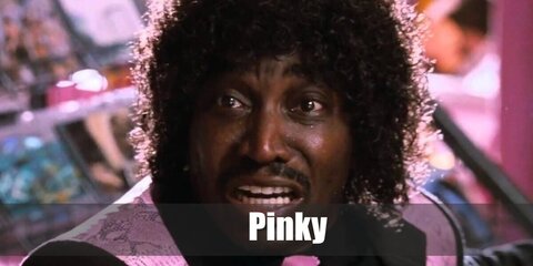  Pinky’s costume is a long-sleeved black button-down shirt with pink cuffs, a two-piece black suit with a vintage pink fabric design on the blazer, pink tuxedo suit shoes, a pink tie, and pink retro glasses.