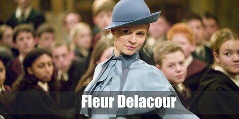 Fleur Delacour wears a blue school uniform with a cape, black stockings, and shoes. She also has blonde hair which she styles with a hat.