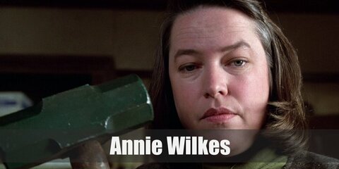 Annie Wilkes costume consist of an olive-colored sweatshirt or jumper paired with a sleeveless wool dress or vest and skirt combination. Wear a wig, black socks, and flat shoes, too. Carry a toy mallet. 