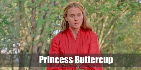 Princess Buttercup wears a long-sleeved red dress with a gold belt. Her hair is blonde and she styles it with a head piece.