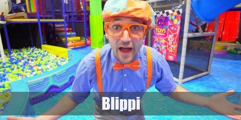 Blippi’s costume is a light blue, long-sleeved, button-down shirt tucked into light grey pants, orange suspenders, an orange bowtie, orange and blue sneakers, and an orange and blue hat.