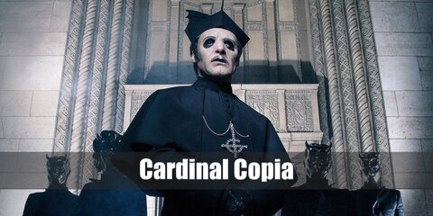 Cardinal Copia wears cardinal or bishop outfit in black and sports dark eye make-up.