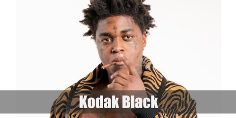 Kodak Black costume gold teeth, an unconventional afro hair ‘do, and lots of tattoos. 