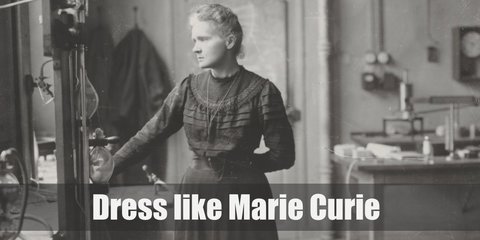 Marie Curie costume is a black conservative long-sleeved gown with a high crew neckline. Her hair is tied in a messy bun. She also wears a minimalist necklace. 