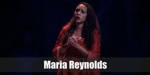Maria Reynolds' stage look features a purely red colonial-era gown. She also has curly hair.