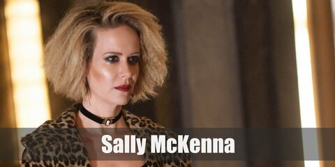 Sally McKenna's costume is leopard-print dress in style with a pair of black stockings ang yellow heels. She also wears a choker and her hair is in a dirty blonde frizz.