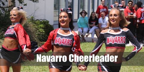 A Navarro cheerleader outfit features a cropped top with long sleeves and NAVARRO in capital letters. They also wear skirt-shorts with white sneakers. 