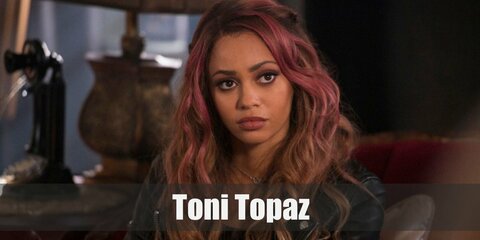  Toni Topaz costume is wearing dark clothes, ripped jeans, and her signature Southside Serpent jacket. Toni Topaz another costume can be recreated with fish net sleeves under a black top paired with black pants. She also wears boots and is known for her pink hair