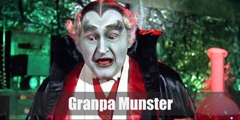 Grandpa Munster's costume features a long cape, white shirt, a jacket and dark pants. He is almost bald and has thick eyebrows and black lips. Complete the costume with a medal.