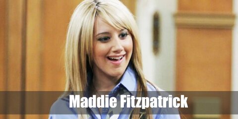 Maddie Fitzpatrick wears a school uniform with a blue shirt, neck tie, plaid skirt, high socks, and shoes. She also has blonde hair.